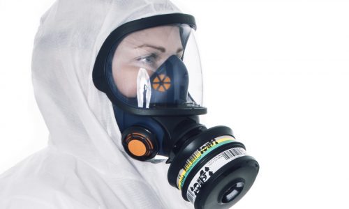 Person med andningsskydd helmask och skyddskåpa