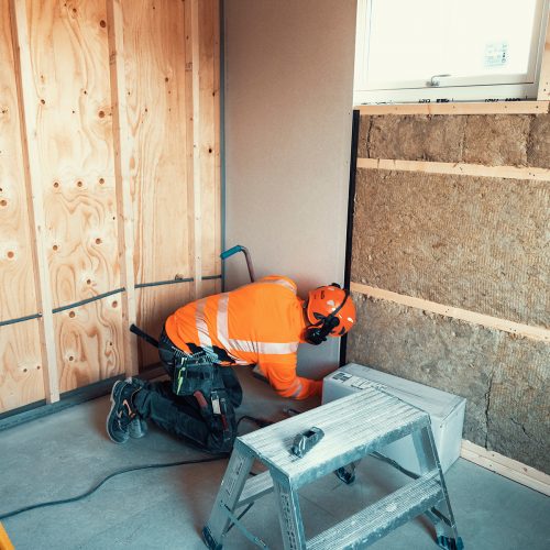 Snickare med skyddshjäm som skruvar gips