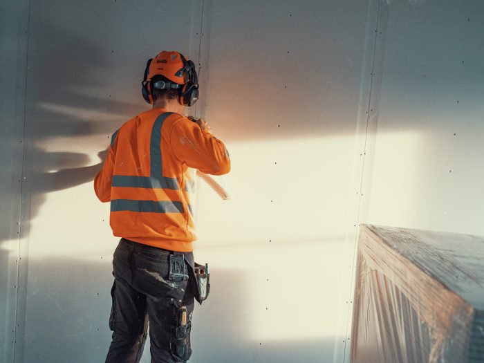 Byggarbetare som skruvar gips.