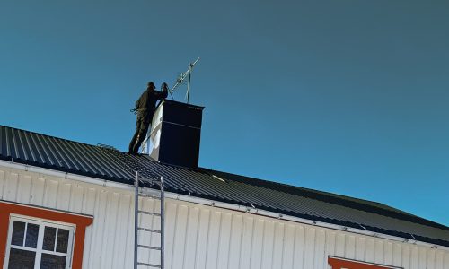 Skorstensfejare som sotar skorsten på tak